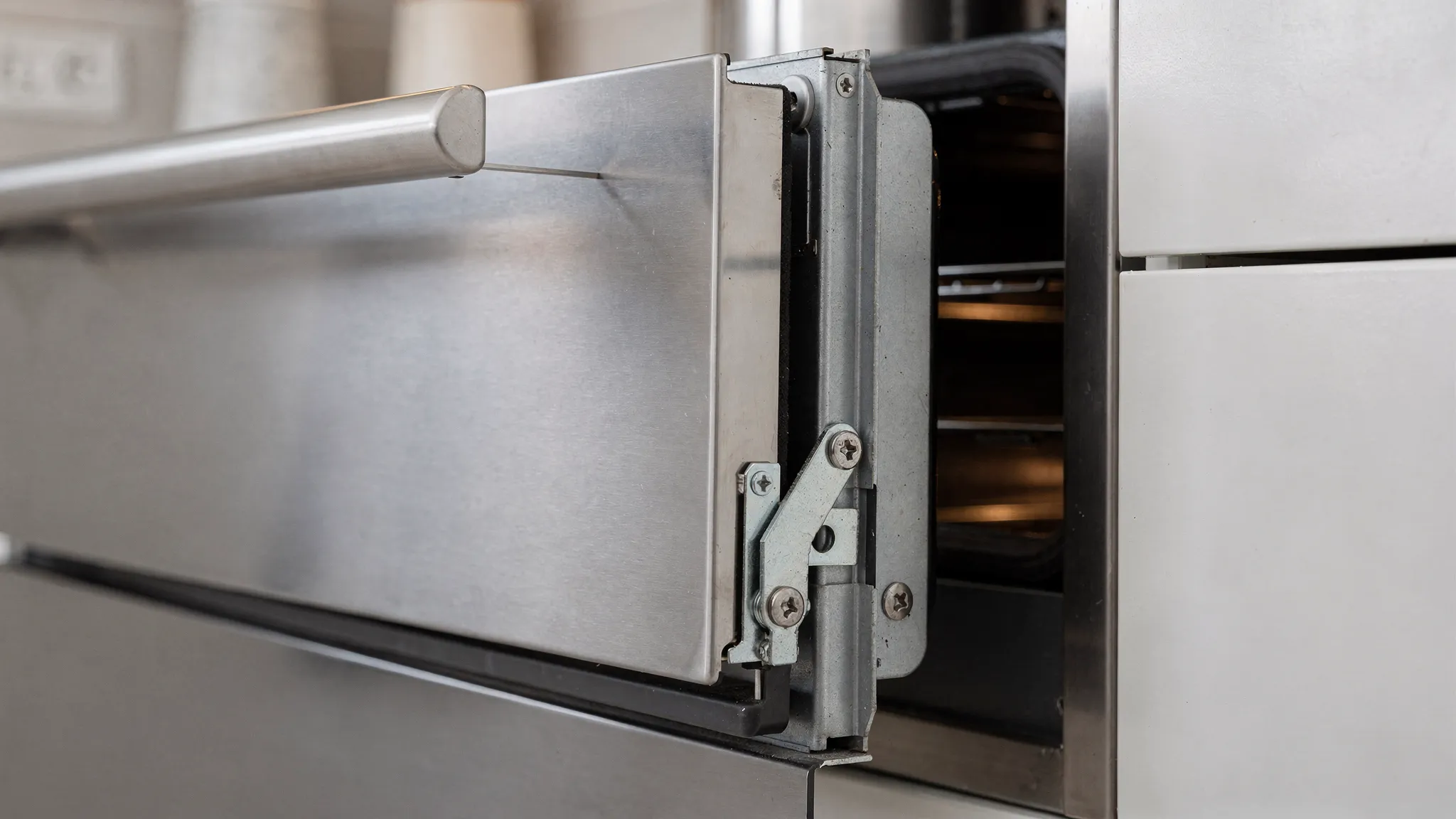 A close-up view of an oven door that is slightly sagging on one side, showing uneven gaps at the corners and highlighting the hinge area where alignment issues are typically visible.