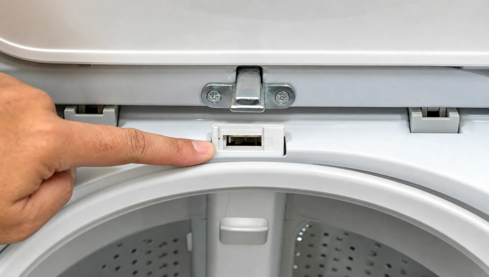 Close-up of the lid strike and latch opening on a top-load washer during a lid lock check.